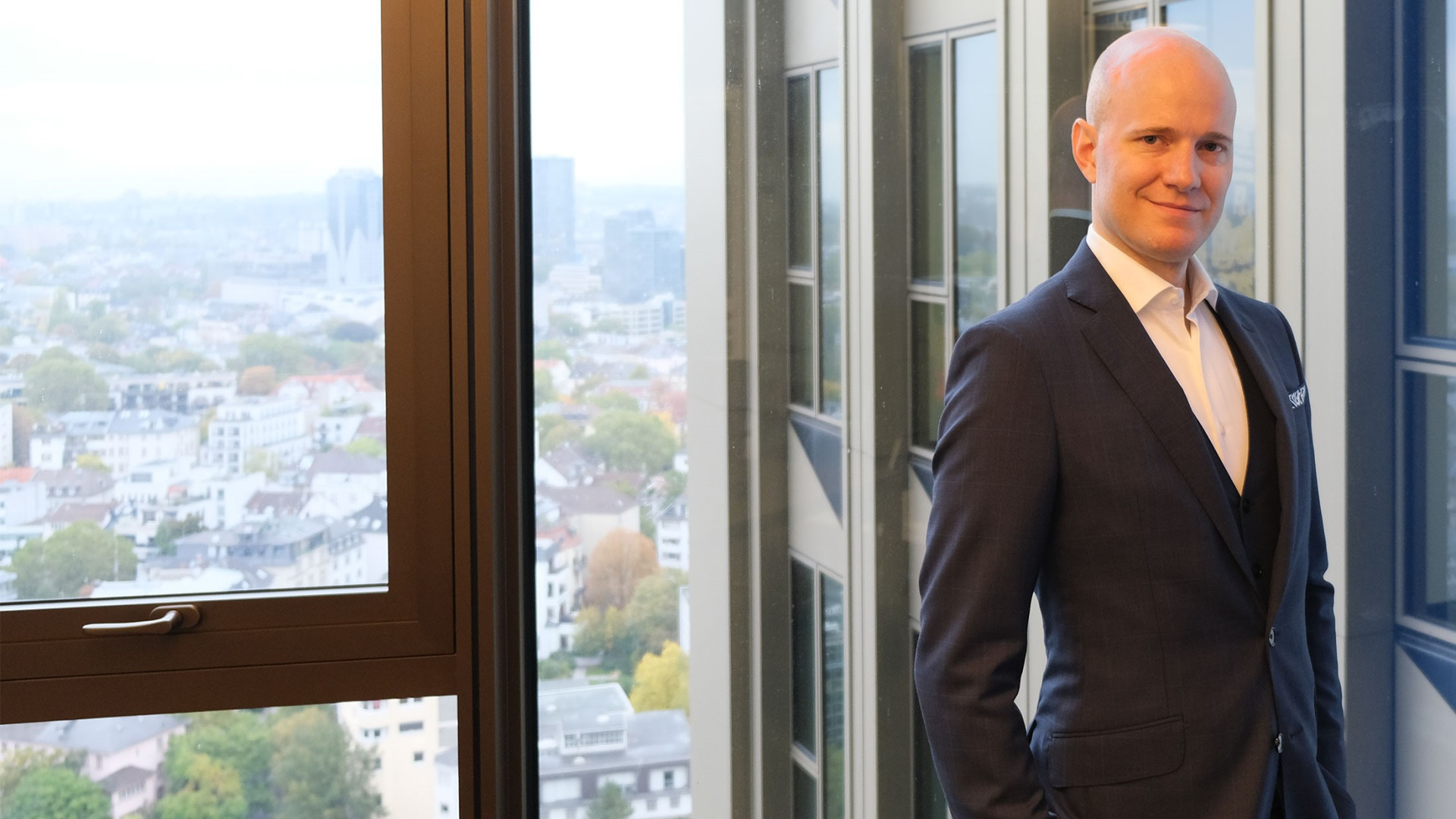 hkp/// group Senior Director Oliver Baierl stands in front of the window front on the 20th floor of Tower 185 in Frankfurt.