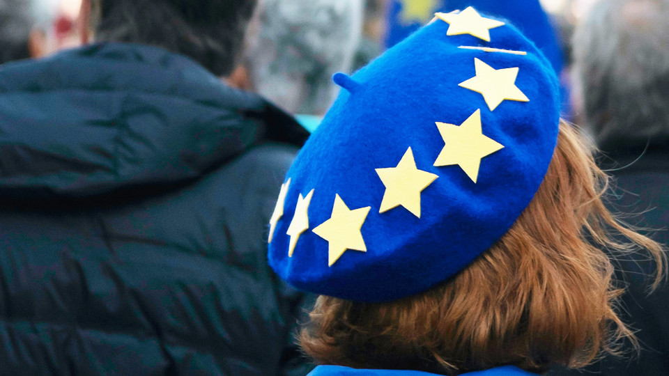 A woman with a Europe beret stands in the middle of a crowd of people.