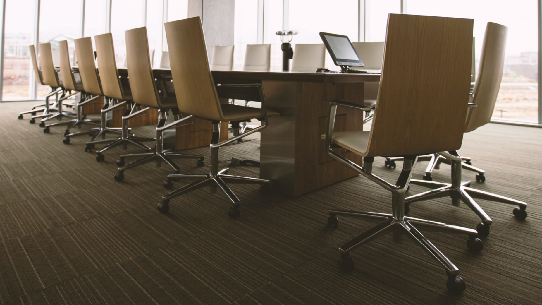 Board Room: Konferenztisch mit Stühlen vor Fensterfront. Webinarserie von hkp/// group und Directors Academy zu den Grundlagen der Aufsichtsratsorganisation und -tätigkeit.